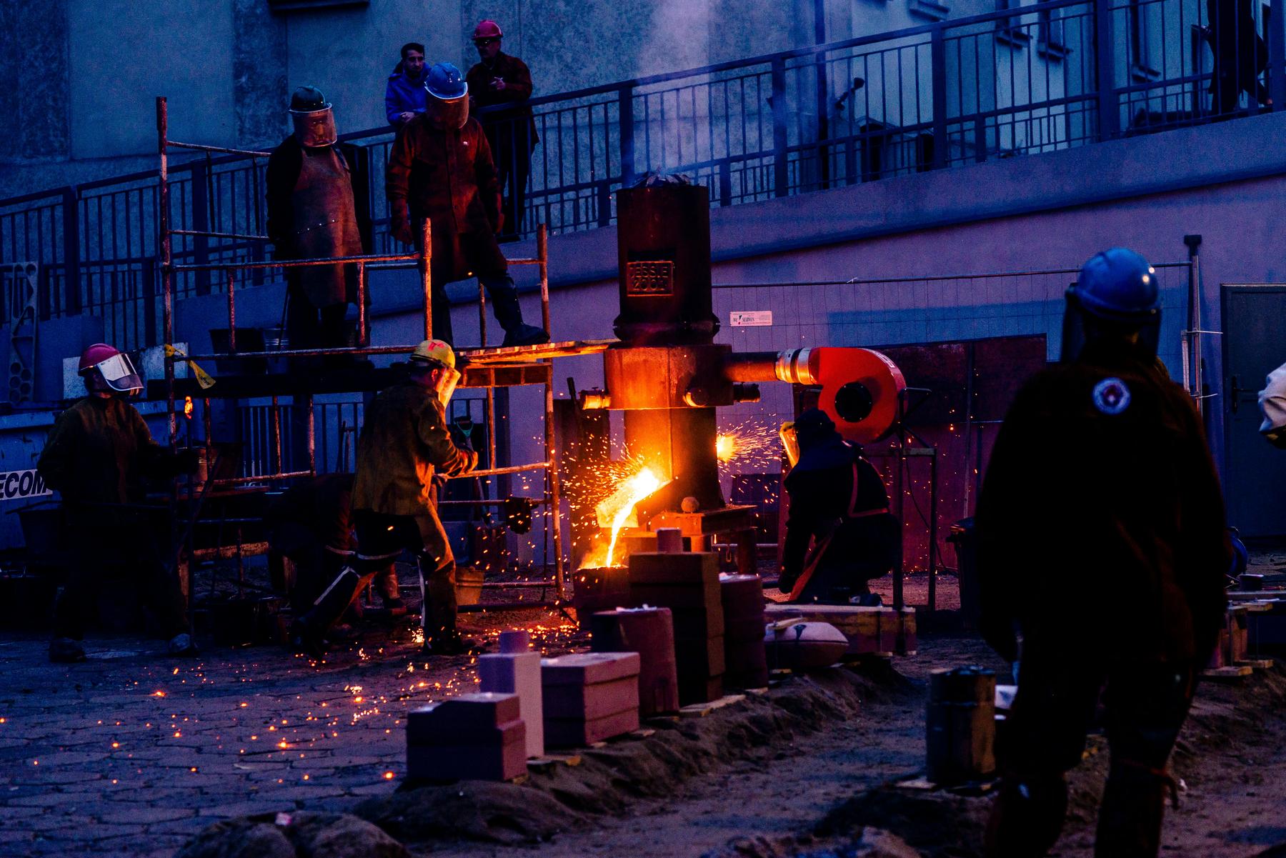 Foundry workers pouring molten metal at dusk